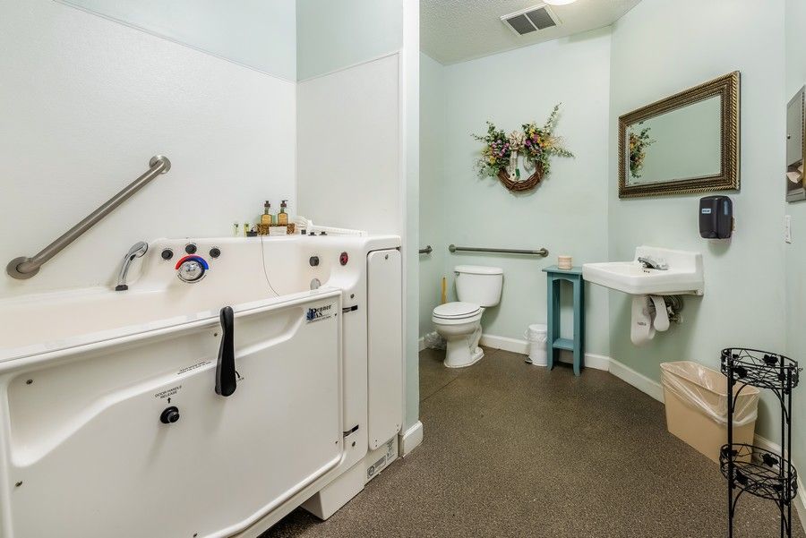 A well-designed accessible bathroom featuring a walk-in tub, toilet, and sink with a decorative mirror.