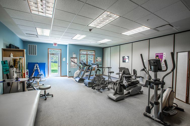 An indoor gym equipped with treadmills, stationary bikes, and elliptical machines.