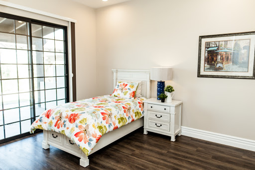 A bright and cheerful bedroom featuring a single bed with colorful floral bedding and white furniture.