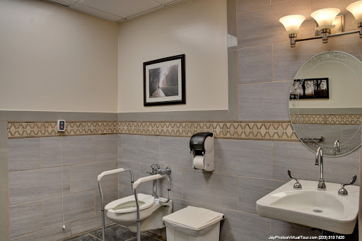 A clean and modern bathroom featuring essential amenities, including a toilet with grab bars for support and a stylish sink.