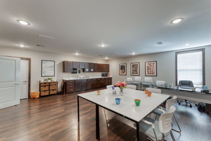 A modern kitchen and dining area with a large table, chairs, and sleek cabinets.