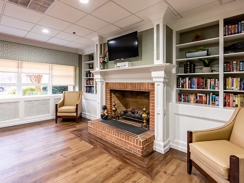 A cozy living room with a brick fireplace, bookshelves, and comfortable armchairs.