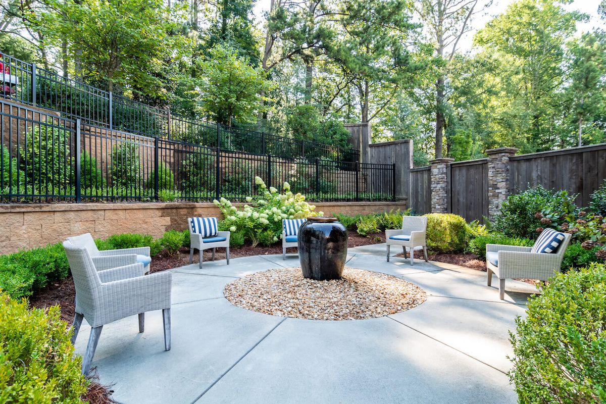 A serene outdoor patio area featuring modern furniture and lush greenery.