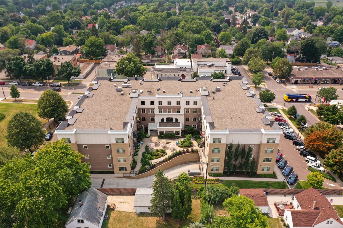Aerial view of a large building surrounded by trees in a residential area.