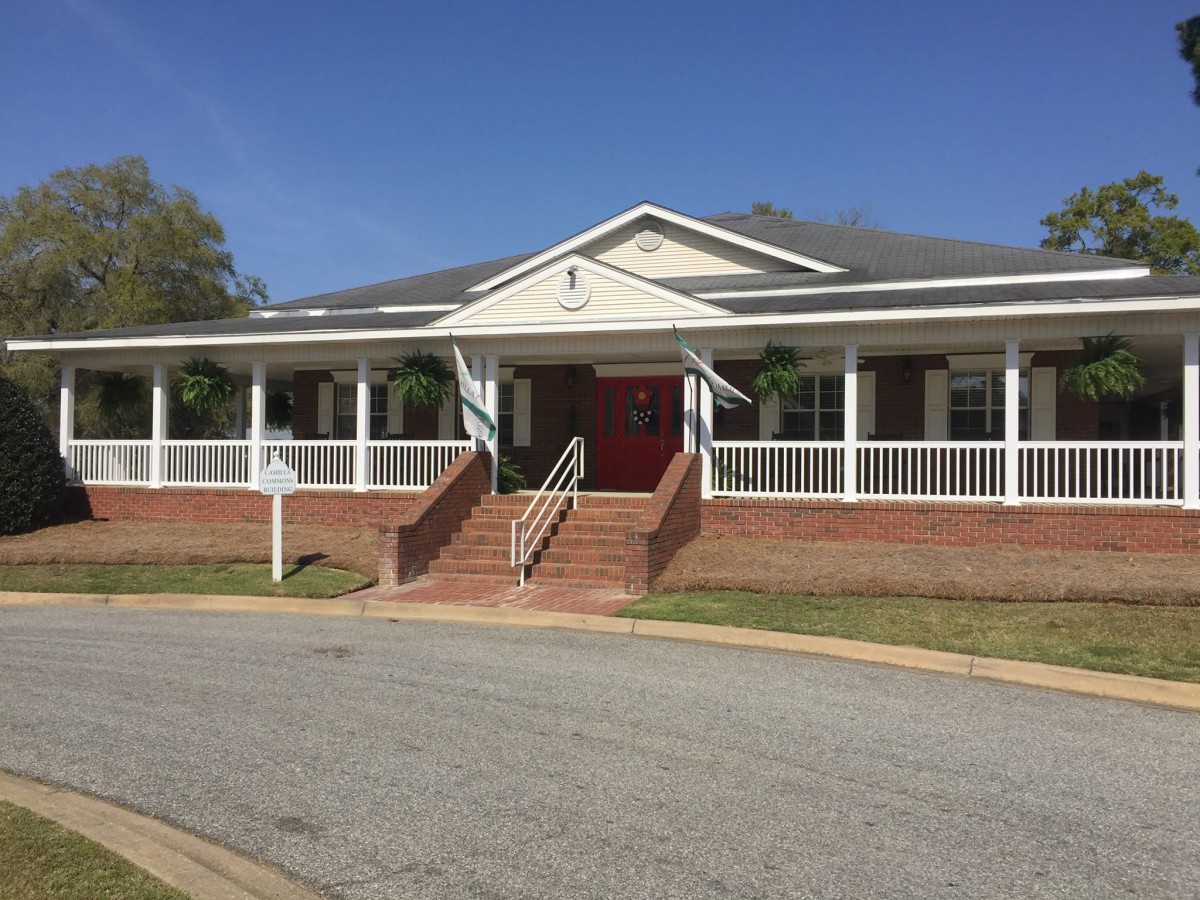 A residential building with a large front porch and red door.