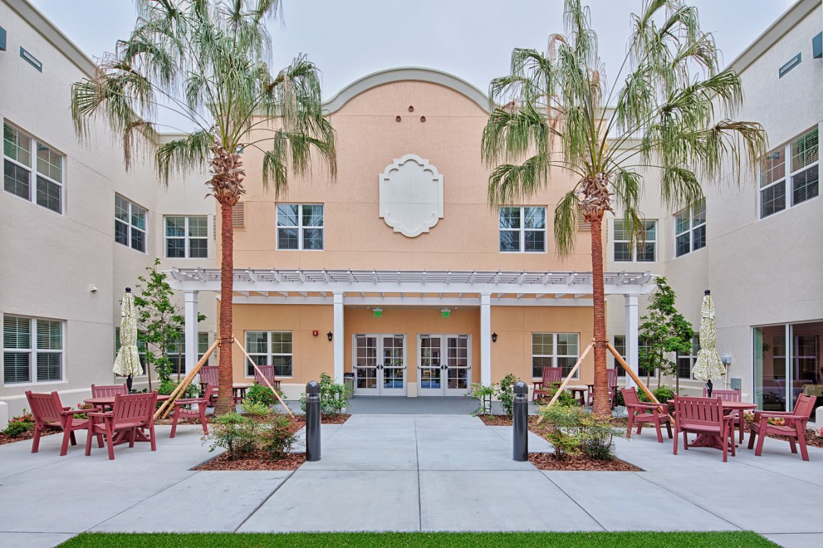 A building entrance framed by palm trees and well-maintained landscaping.