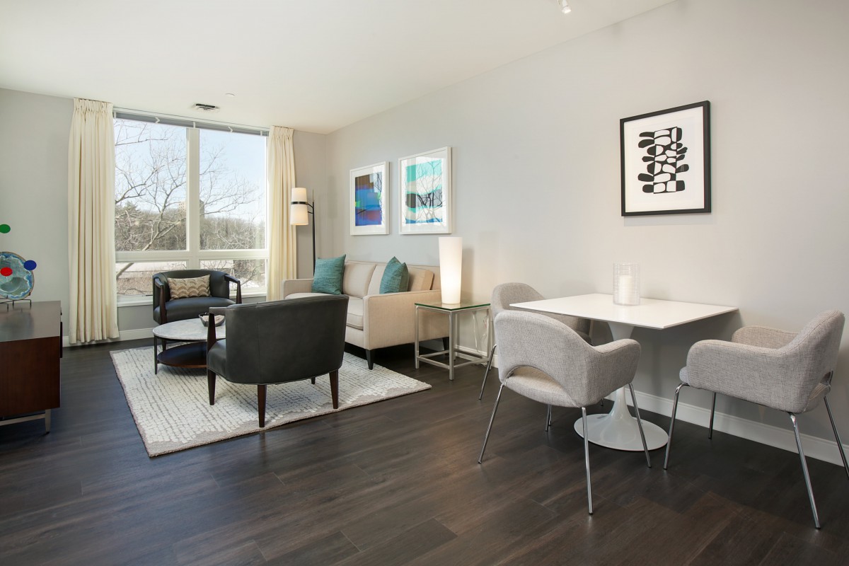 A modern living and dining area with contemporary furniture, artwork on the walls, and ample natural light.