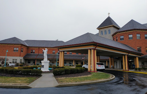 A view of a church building featuring a statue and beautifully landscaped surroundings.