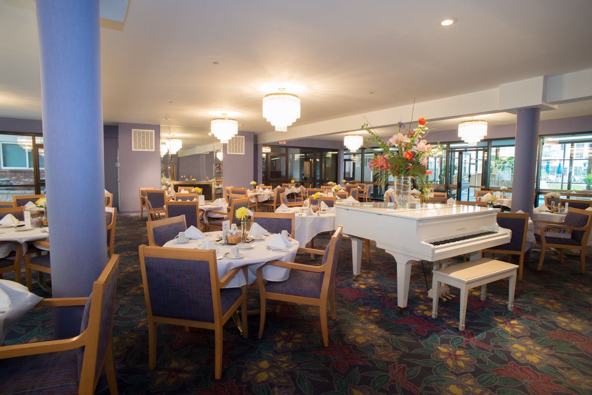 Elegant dining area with a grand piano and beautifully set tables.