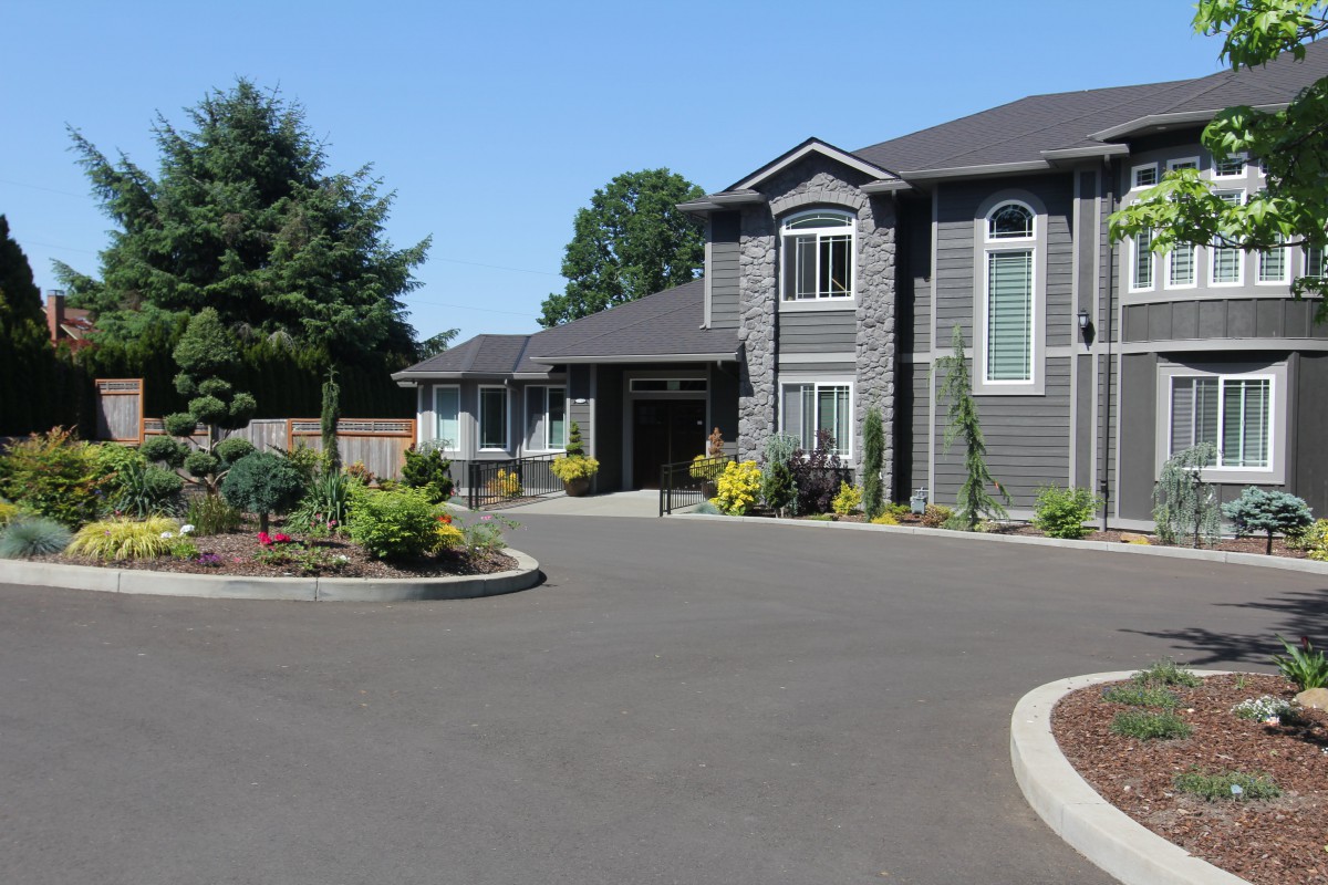 A large residential home with a landscaped driveway under a clear blue sky.