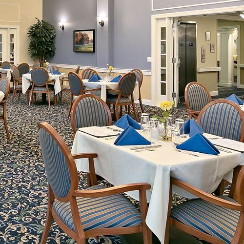 An elegantly set dining area with tables and chairs, featuring blue napkins and tasteful decor.