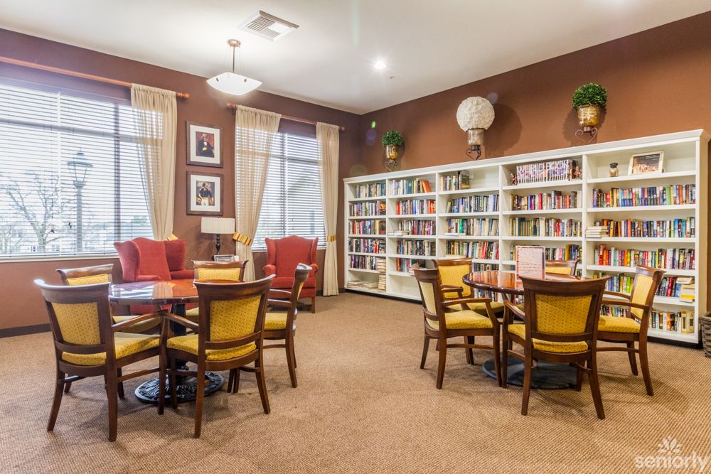 A cozy library reading room with bookshelves, tables, and chairs.