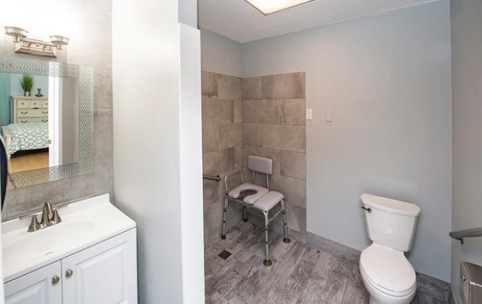 A modern bathroom featuring an accessible shower with a shower chair.
