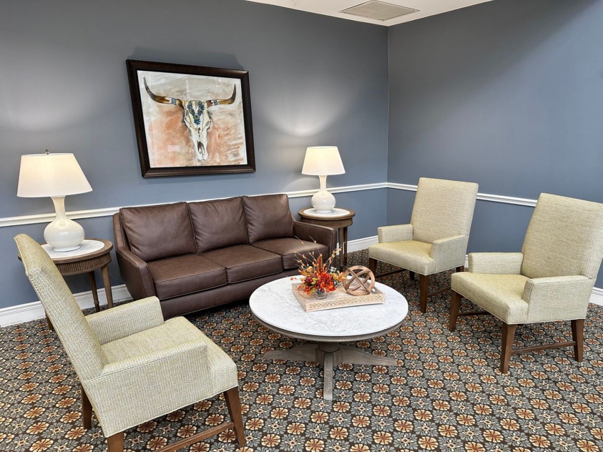 A cozy living room with a brown sofa, armchairs, and a decorated coffee table.