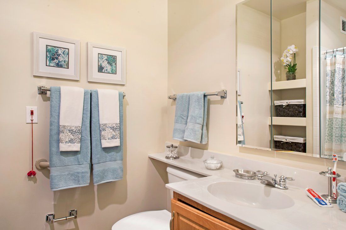 A neatly organized bathroom with blue towels and decorative accents.
