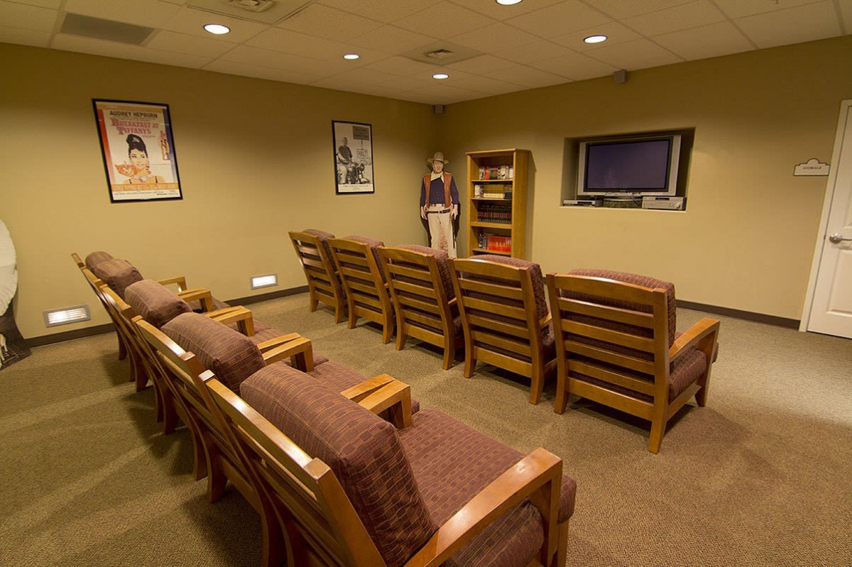 A waiting room with rows of chairs facing a television on the wall.