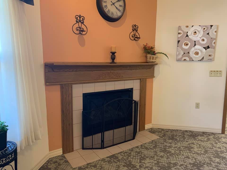 A cozy living room with a fireplace featuring an orange accent wall and decorative elements on the mantel.