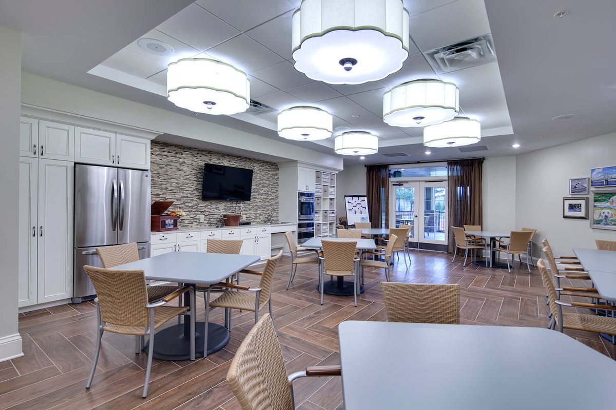 A spacious and modern kitchen with a dining area, featuring sleek lighting fixtures and contemporary furniture.