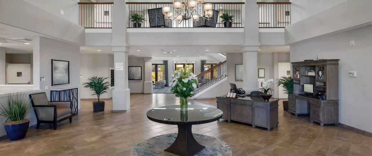 Elegant lobby with a central table decorated with flowers and a grand staircase.