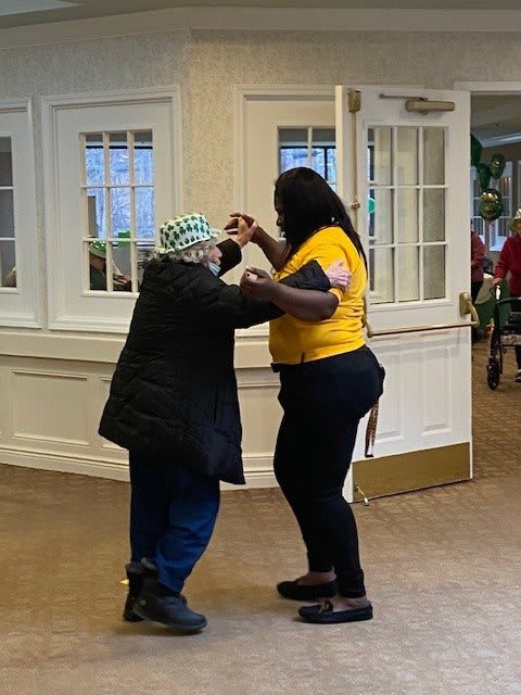 Two people dancing together in a care facility, showcasing intergenerational joy.