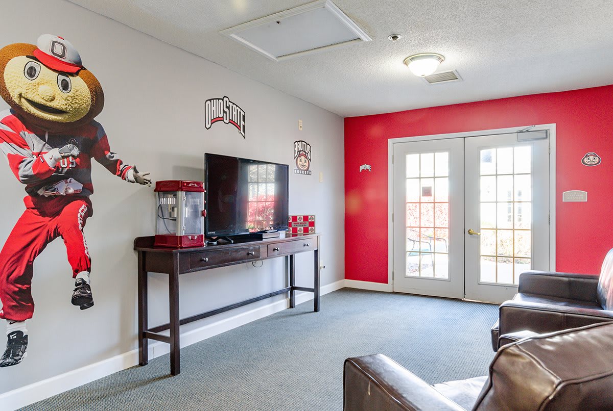 A cozy living room featuring a television and a popcorn machine with bright red accents and French doors.