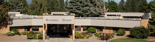 A welcoming entrance to a modern building surrounded by greenery and colorful flowers.