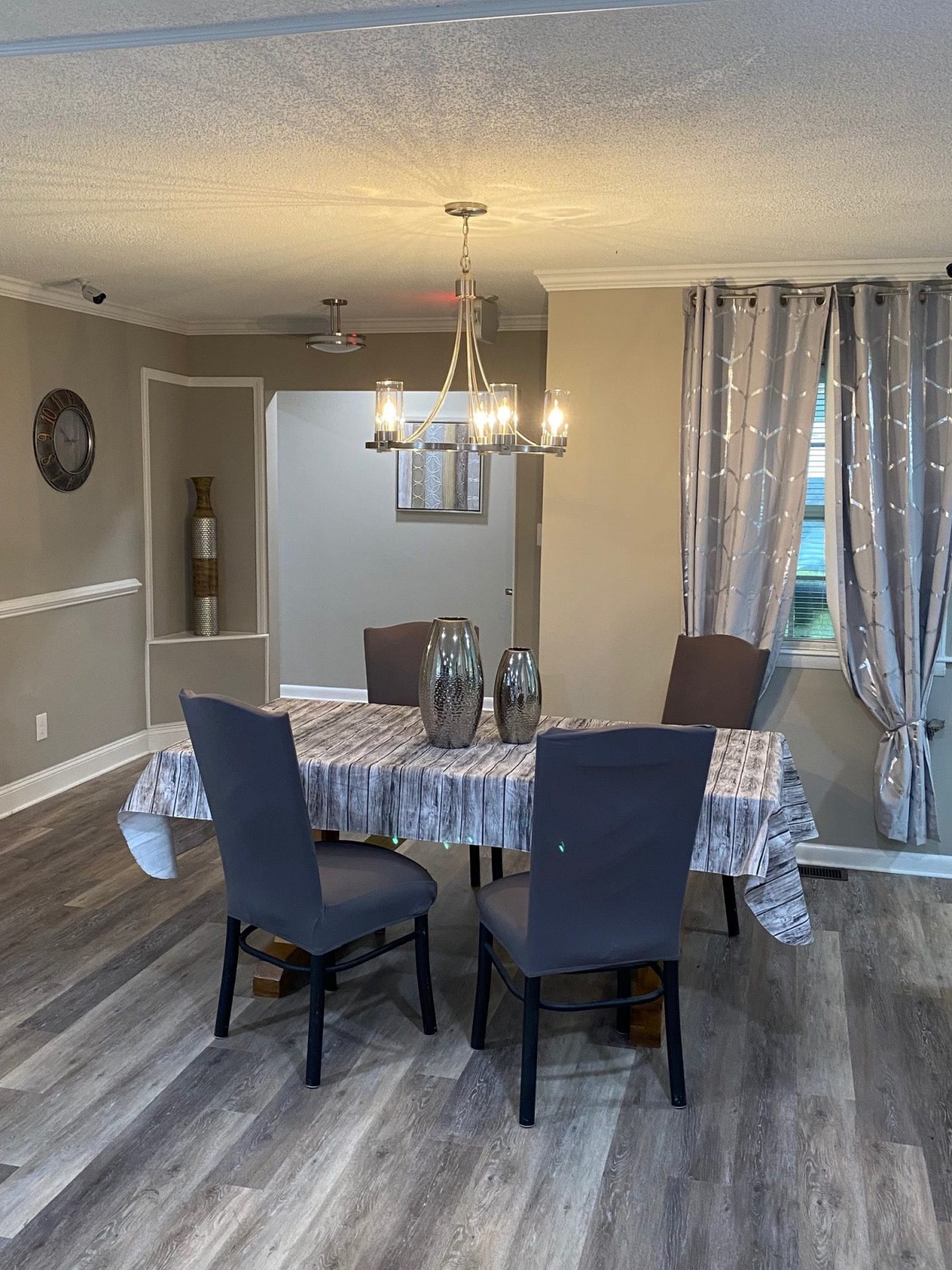 A cozy dining room with a table, four chairs, and a chandelier overhead.