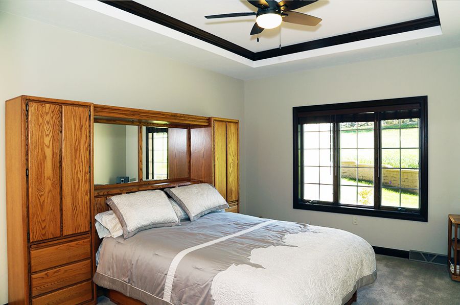 A cozy bedroom with a wooden headboard and ceiling fan.