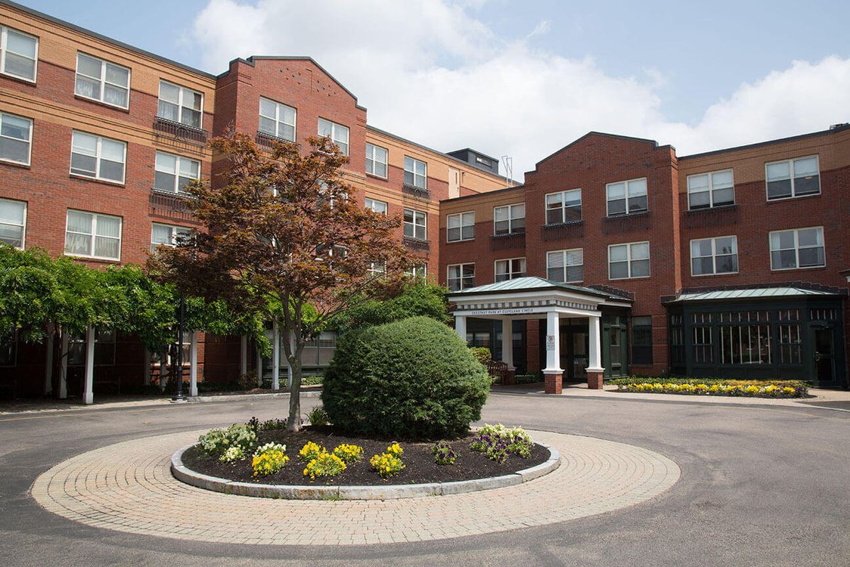 Exterior view of a hotel with landscaped gardens and a roundabout.