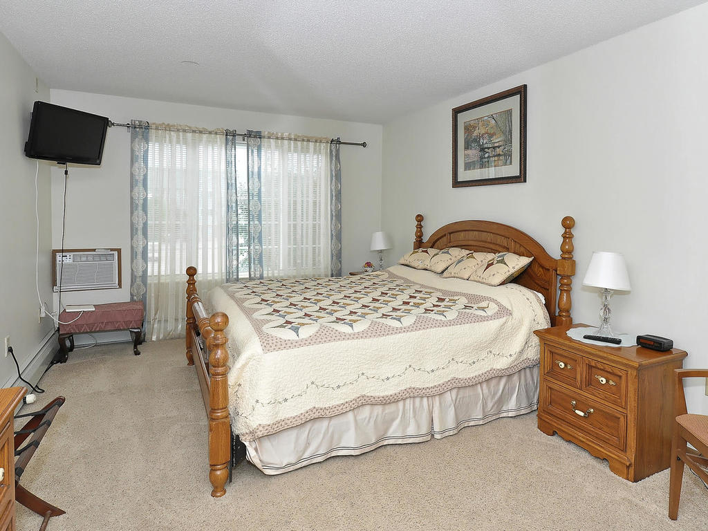 A cozy bedroom with a wooden bed frame, patterned bedding, and matching nightstands.