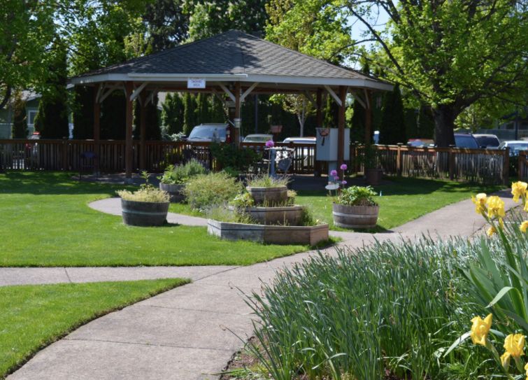 A peaceful garden scene featuring a gazebo surrounded by lush greenery and a winding pathway.