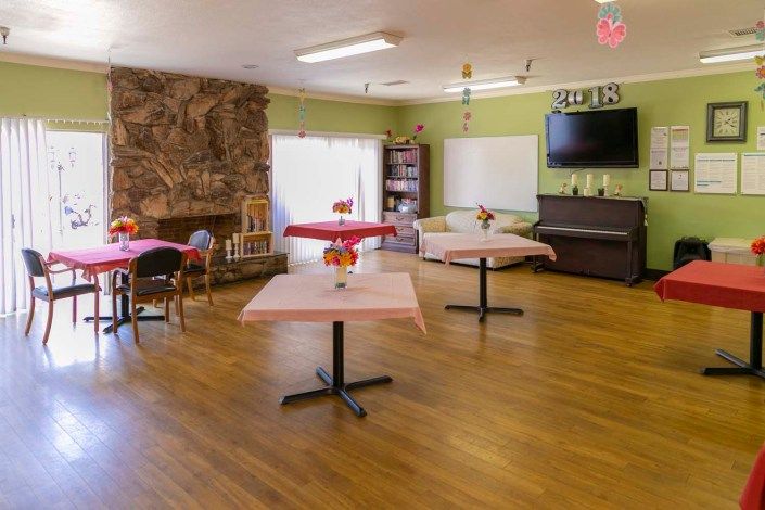 A cozy and spacious dining area with tables, chairs, and a television.