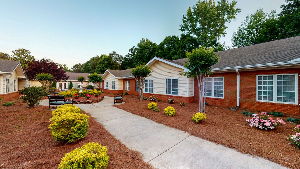 A well-maintained residential area with landscaped gardens, a paved walkway, and brick buildings.
