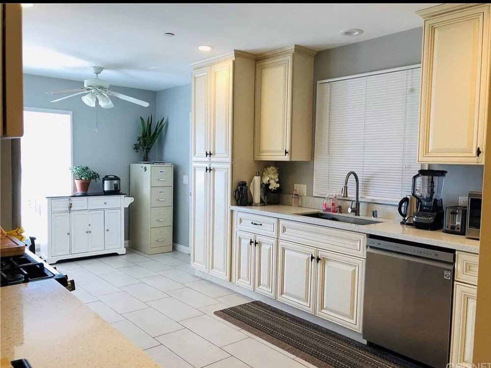 A modern kitchen with white cabinets, a sink, and stainless steel appliances.