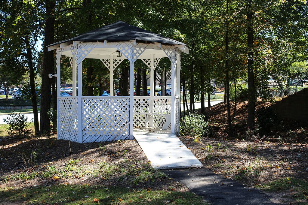 A white gazebo situated in a wooded park area.
