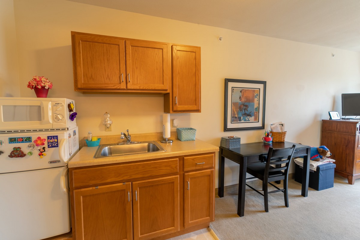 A cozy kitchen area with wooden cabinets, a sink, and a small dining table with chairs.