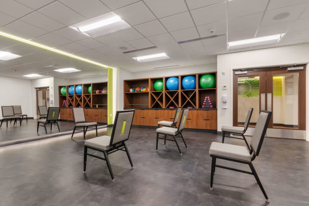 A modern fitness center with chairs and colorful exercise balls neatly arranged along the wall.