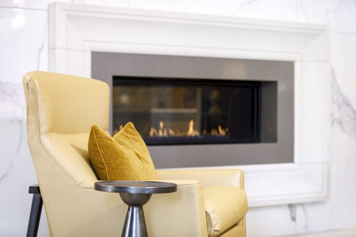 A modern living room with a cozy chair and a sleek fireplace.