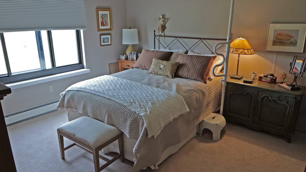 A cozy bedroom with a neatly made bed, nightstands, and soft lighting.