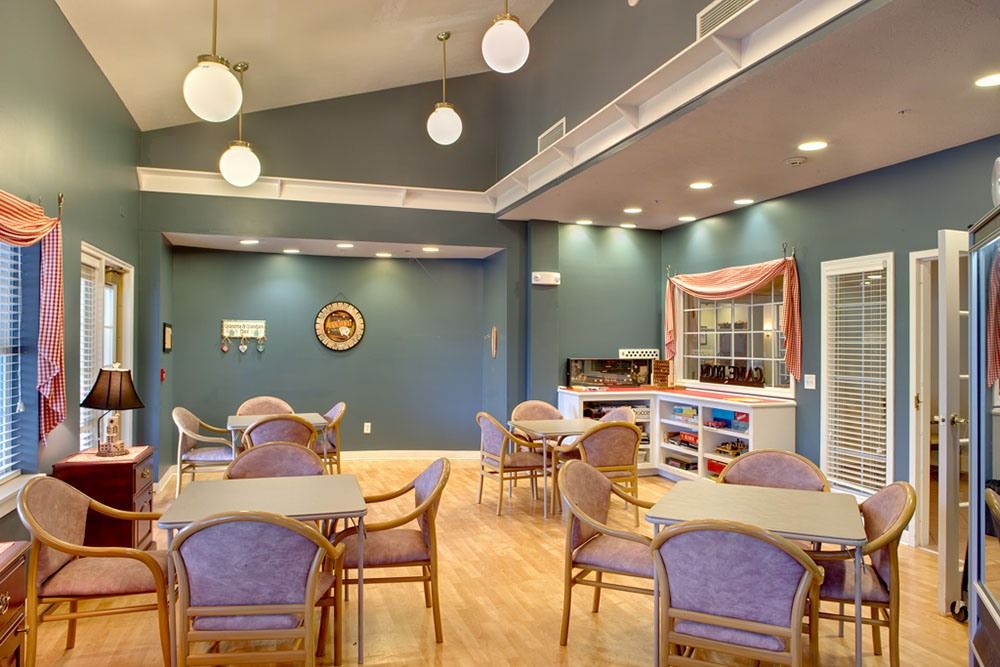 A well-lit dining area with neatly arranged tables and chairs, featuring modern decor and a high ceiling.