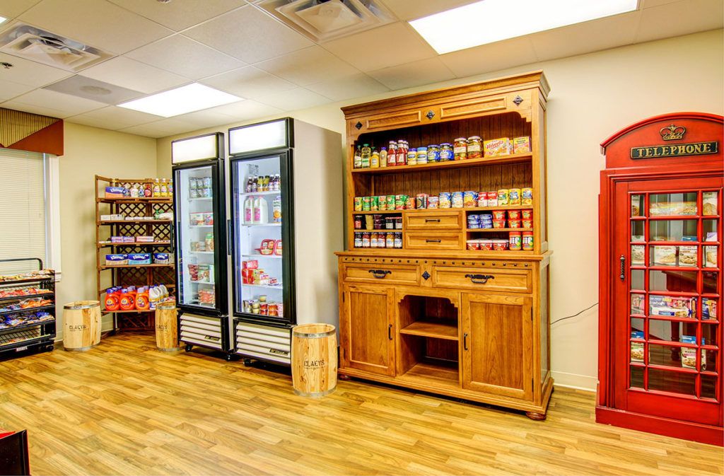 A small store interior featuring wooden shelves and a fridge stocked with various products.