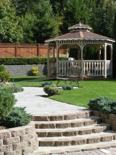 A tranquil garden featuring a gazebo and a well-maintained lawn with a stone pathway.
