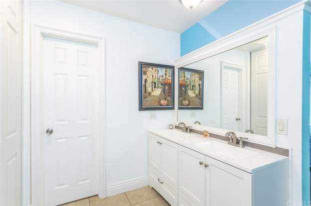 A modern bathroom with a double sink vanity, framed artwork, and a large mirror.
