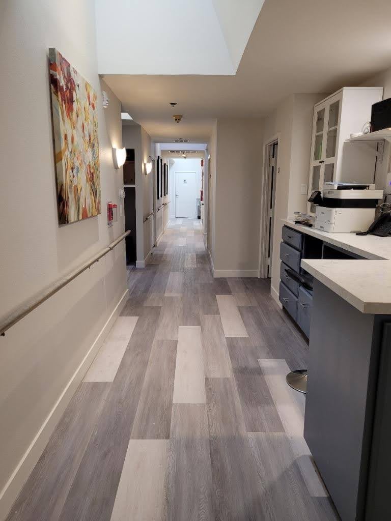 A modern hallway with a kitchen area and artwork displayed on the wall.