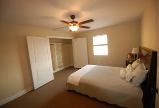 A cozy bedroom with a bed, carpet, and ceiling fan.