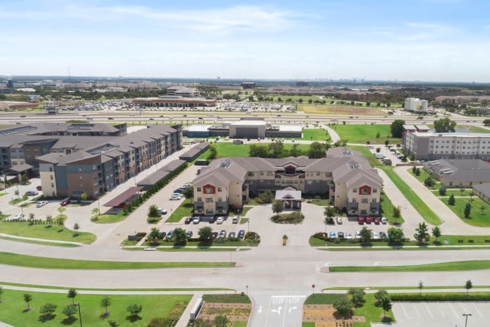 Aerial view of a suburban building complex with a parking lot and surrounding green spaces.