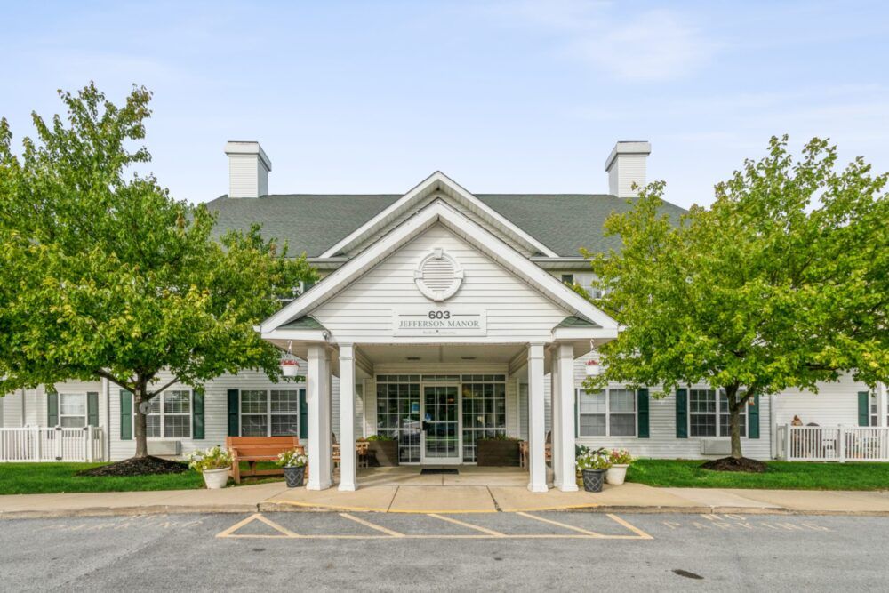 Front entrance of a building with a peaked roof and surrounding trees.