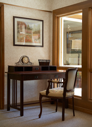 A cozy and elegant home office setup featuring a wooden desk and chair, complemented by natural light from the window.