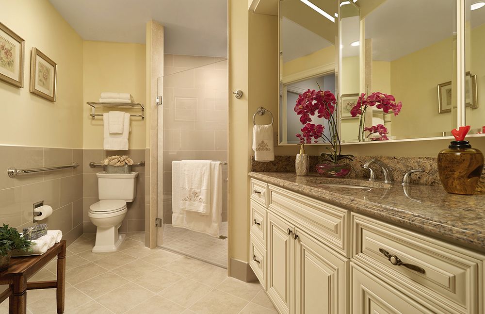 A well-appointed bathroom with elegant cabinetry, a large mirror, and a glass-enclosed shower.