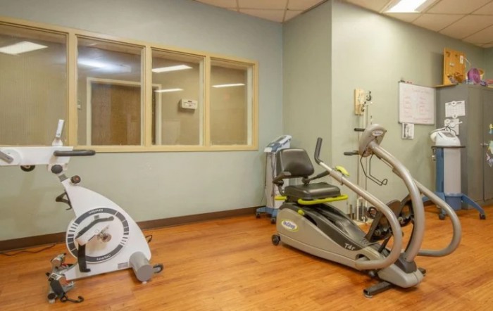 A small gym with various exercise equipment including a stationary bike and fitness machines.